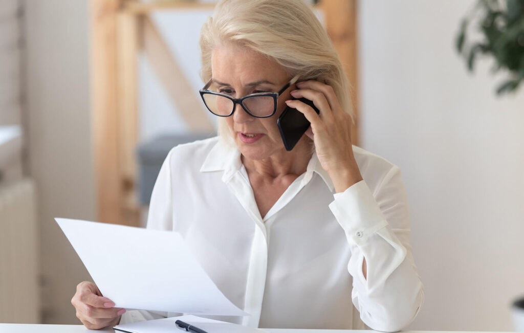 woman speaking on phone while looking at paperwork